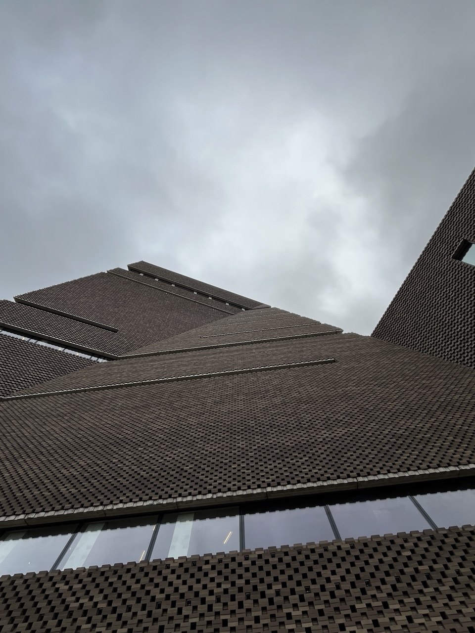 Textured brick building rising into an overcast sky